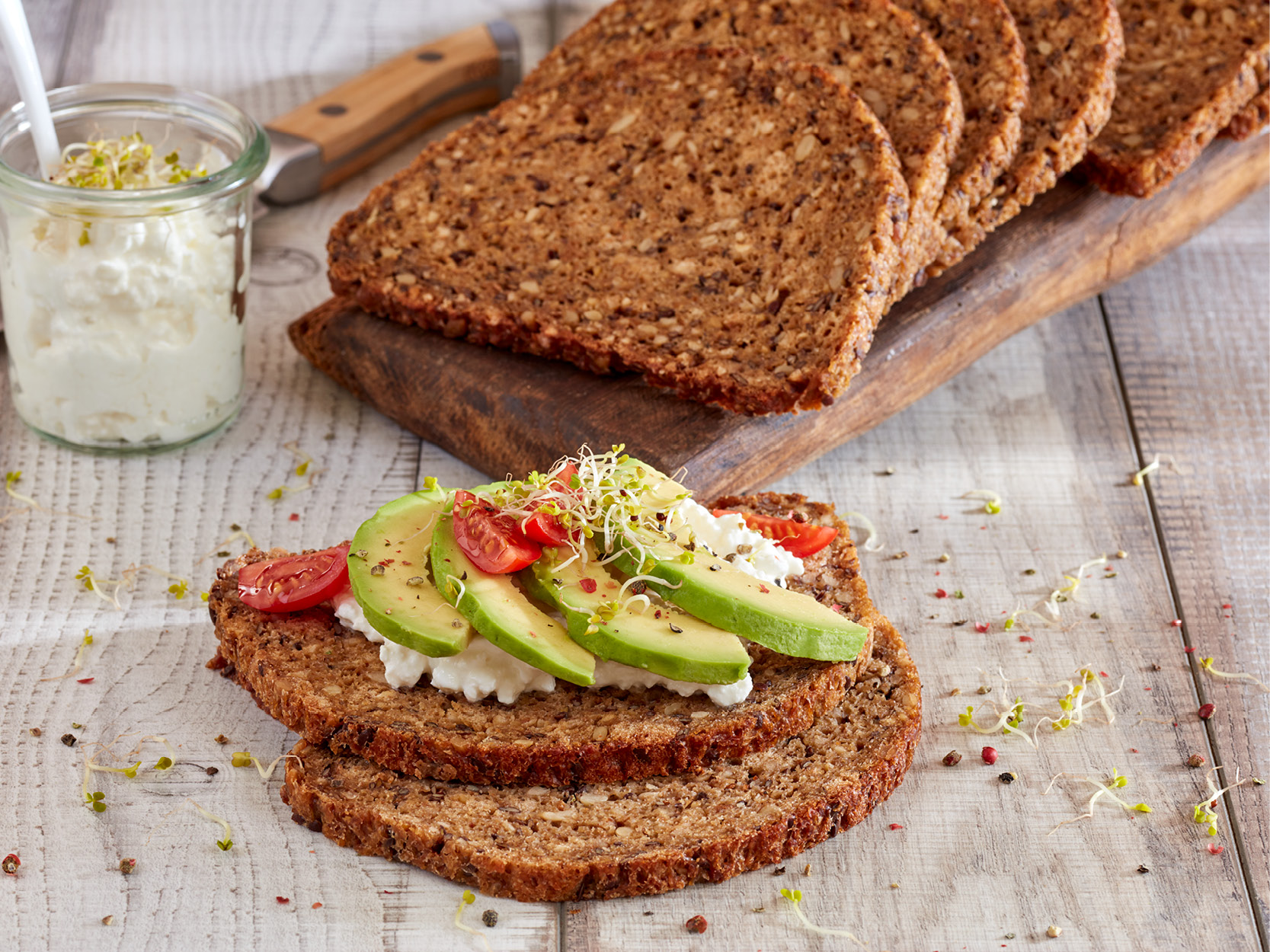 Eiweiß-Schnittbrot. Belegt mit körnigem Frischkäse, Avocado-Scheiben und frischen Sprossen