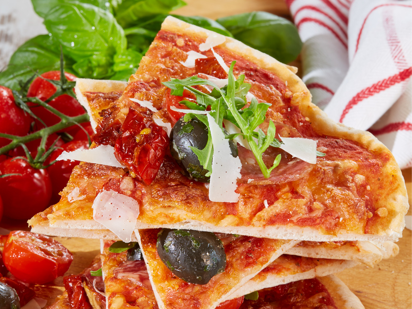 Glutenfreie Pizza, belegt mit Tomaten, Oliven, Rucola und Parmesan