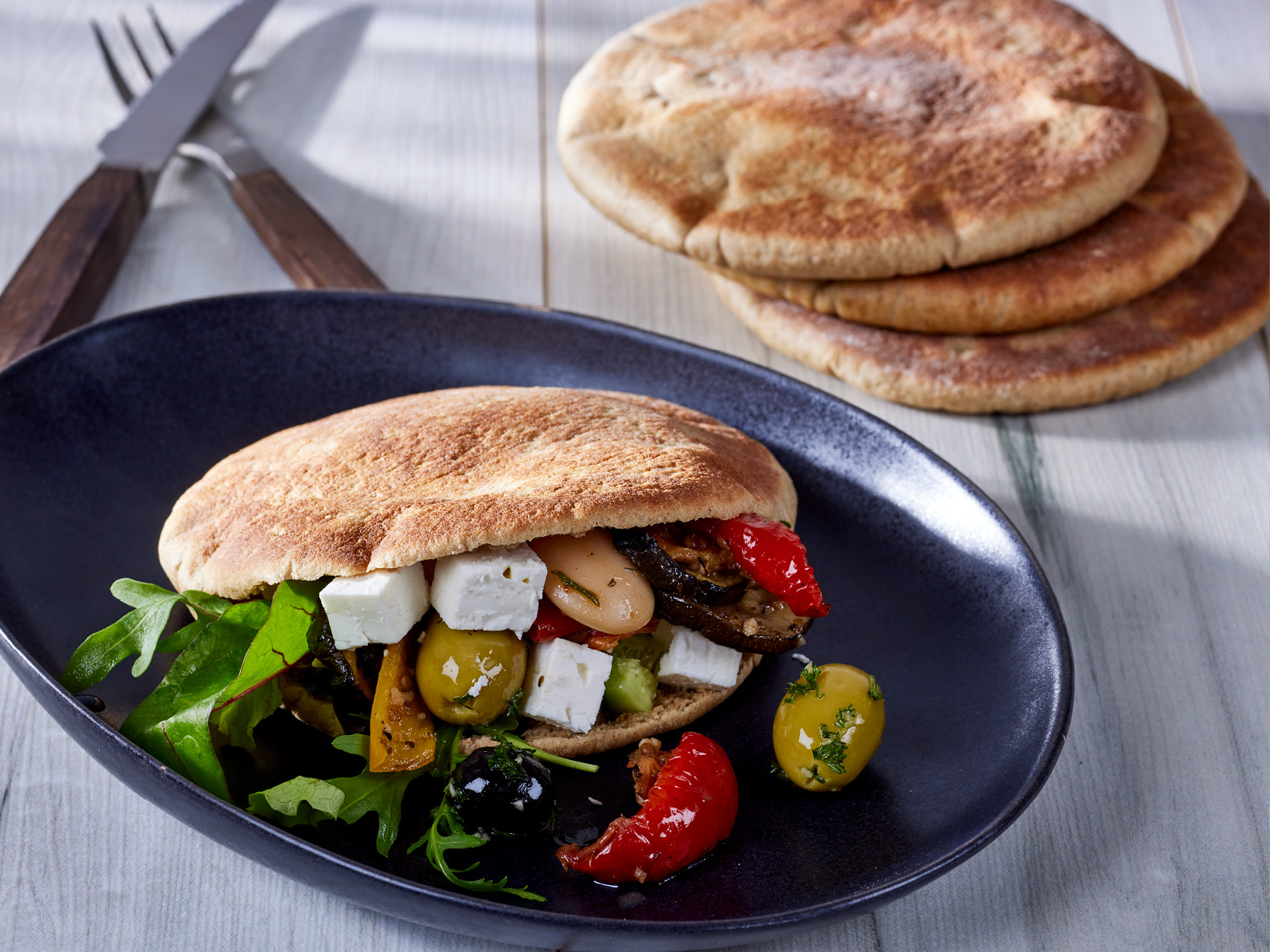 Protein Fladenbrot, Pita, aufgeschnitten und gefüllt mit Feta, Oliven, Grillgemüße
