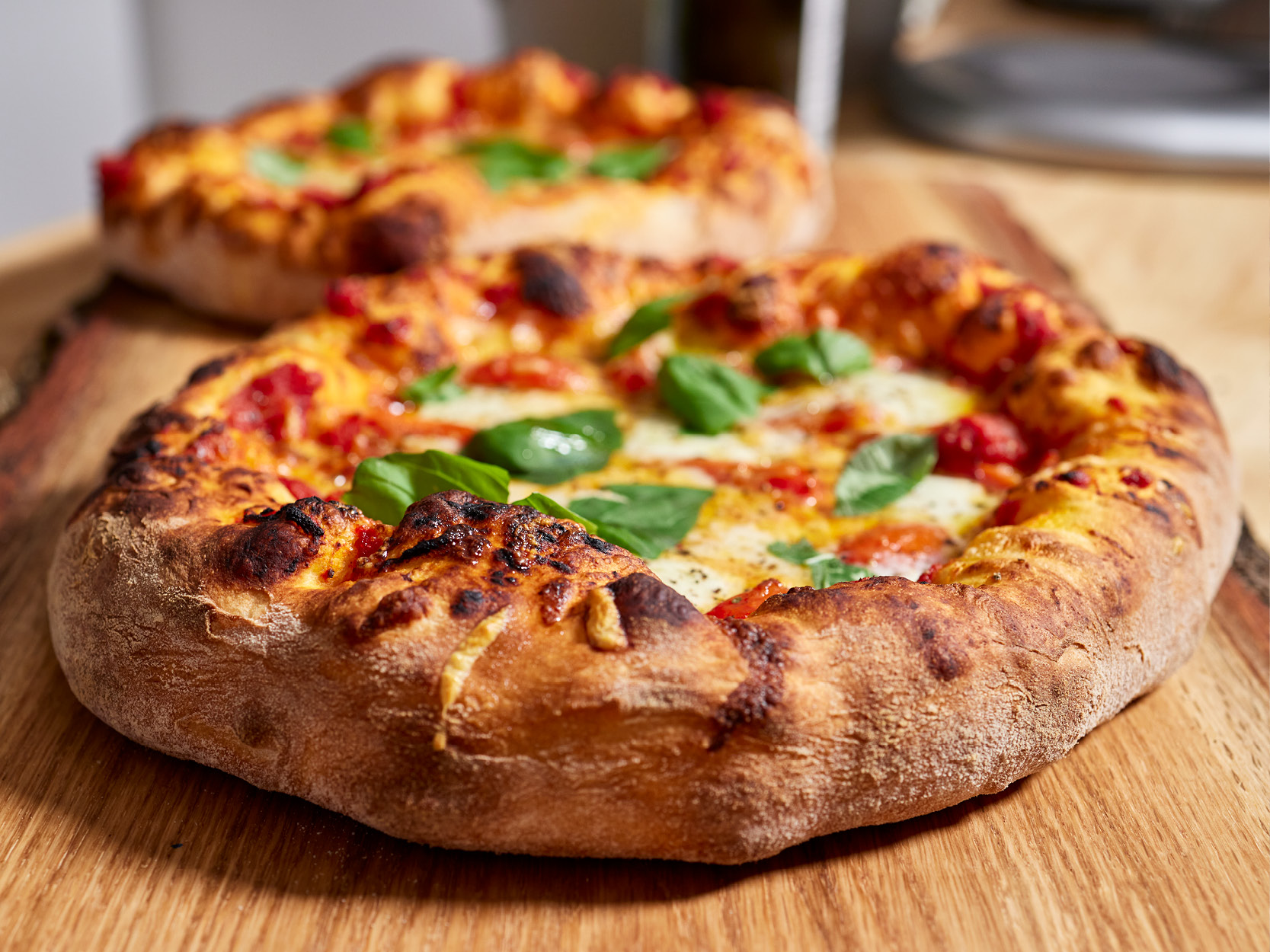 Zwei Pizzen, belegt mit Tomate und frischem Basilikum aus der Serie "Time 4 Taste"