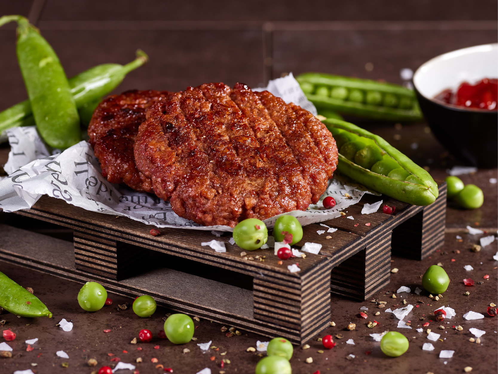 zwei mal gebratener veganer Patty, mit Erbsen als Dekoration